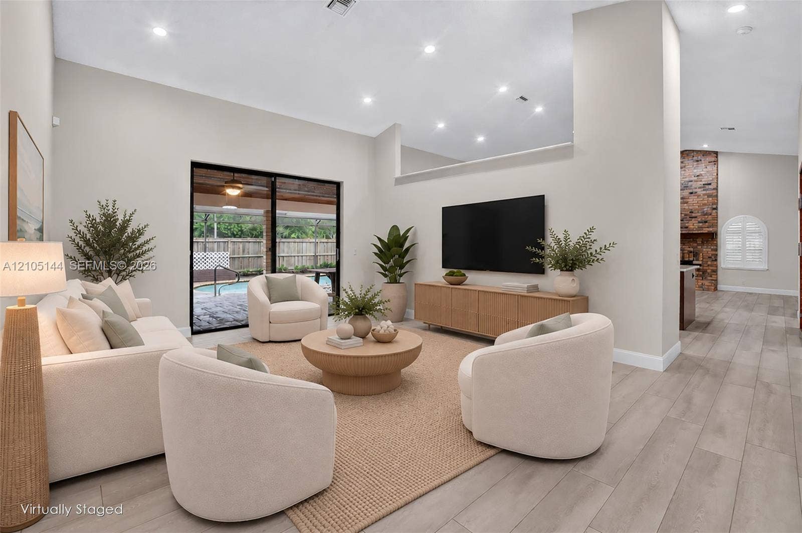Living area featuring vaulted ceilings, recessed lighting, wood-finish flooring, sliding glass door, and exposed brick column