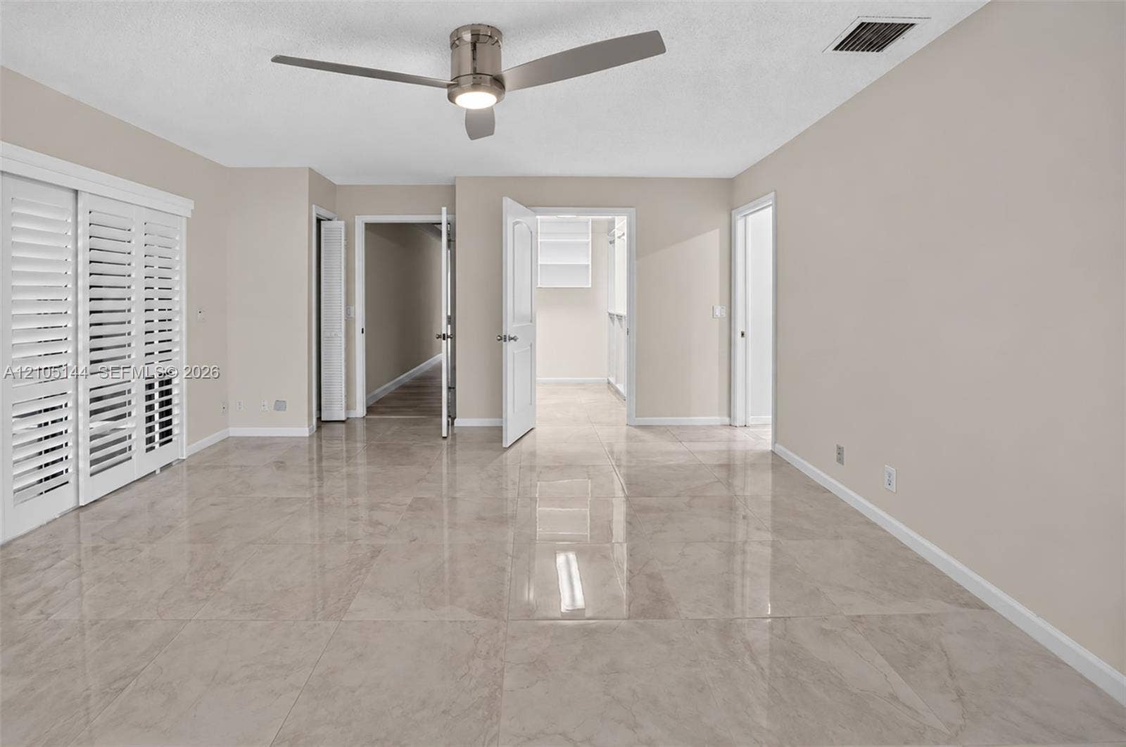 (FAN VIRTUALLY STAGED AS SIMILAR PIECE WILL BE INSTALLED) Interior space featuring high-gloss tile flooring, white plantation shutters, and a modern brushed-nickel ceiling fan with integrated lighting