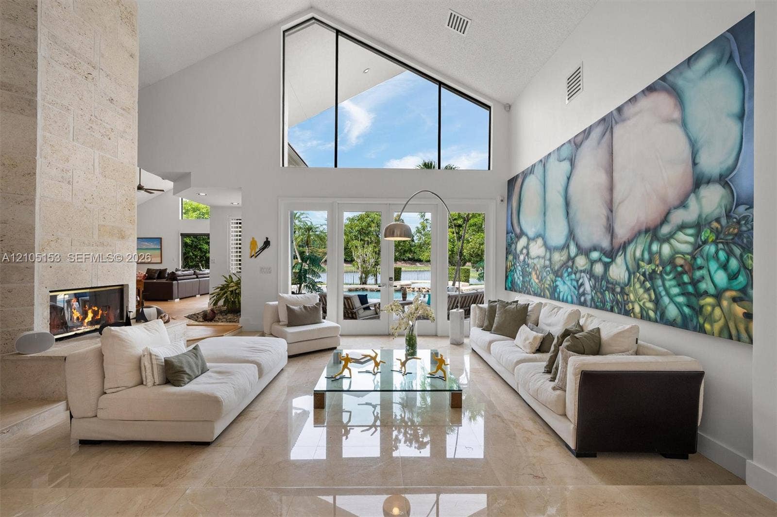 Vaulted ceilings with expansive transom windows, large glass patio doors, a built-in fireplace with stone surround, and polished floor tiles