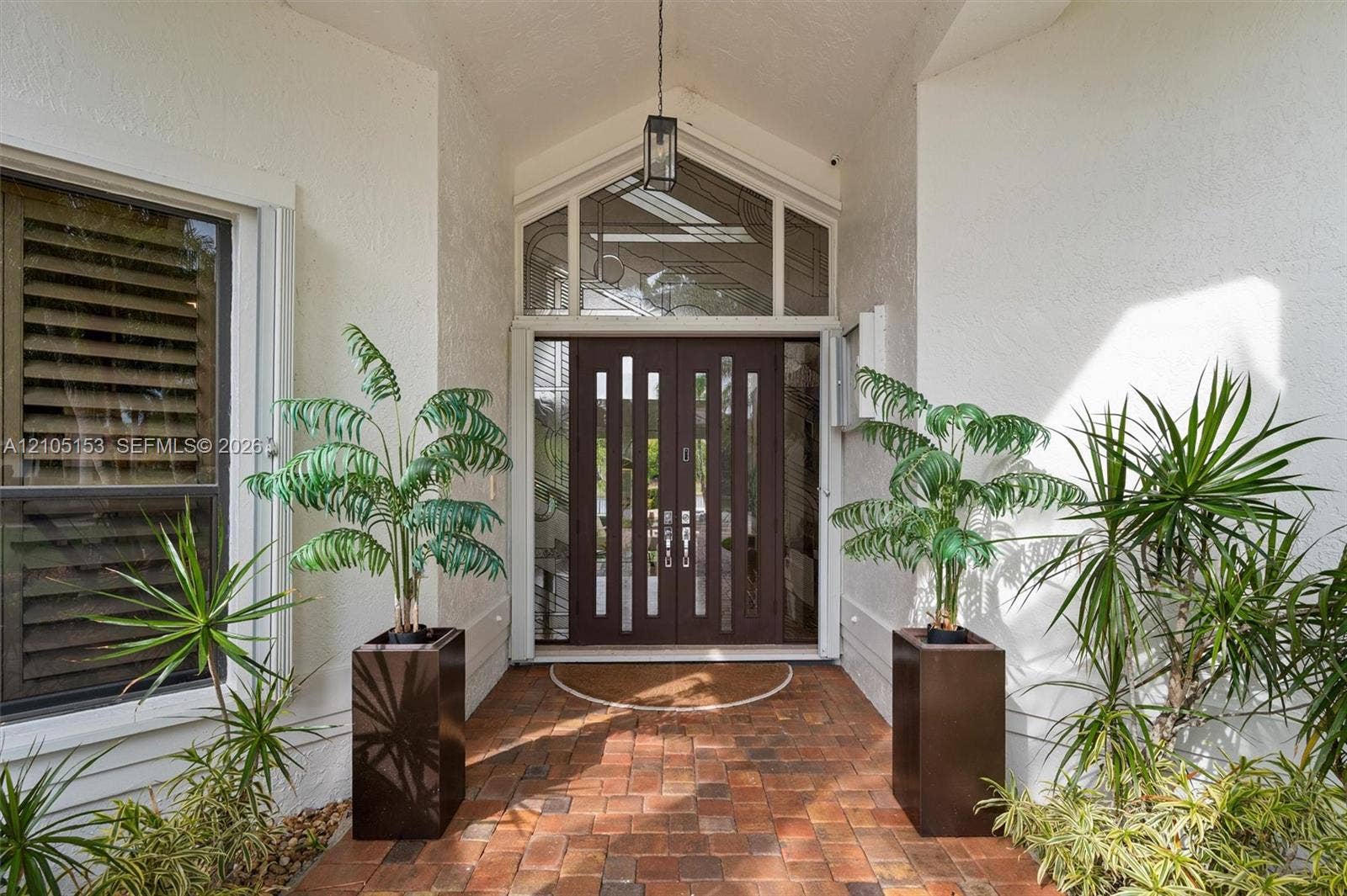 Arched entry with a double-door entry, transom window, and brick paver walkway