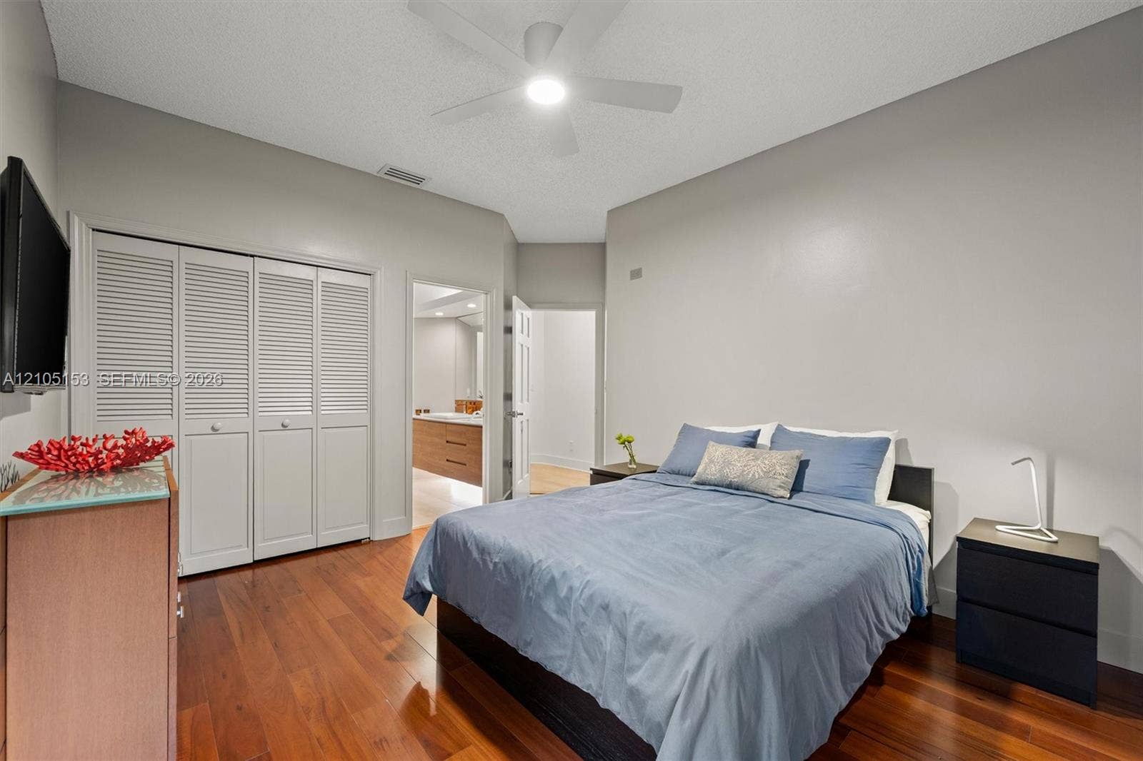 Wood-finish flooring, louvered closet doors, and an attached ceiling fan