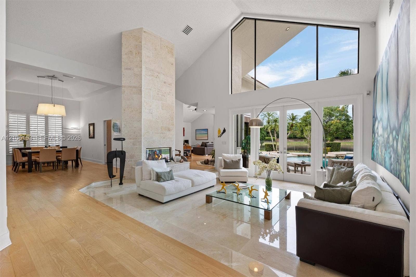 Expansive living area featuring vaulted ceilings, a stone-clad fireplace, and large sliding glass doors
