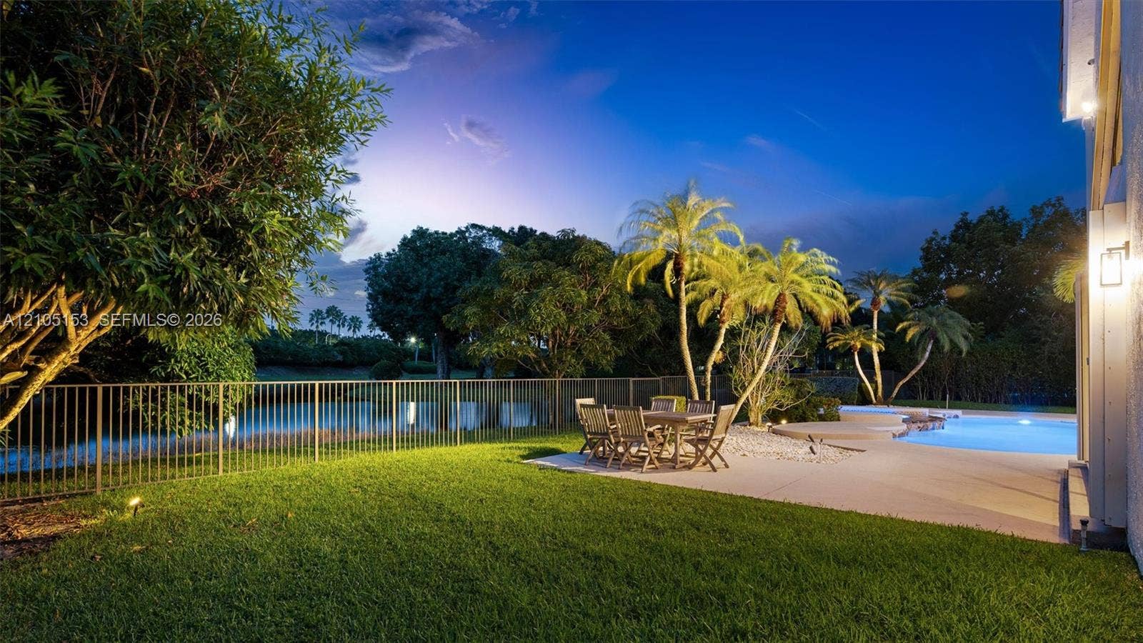Expansive lawn with a metal fence, bordering a body of water
