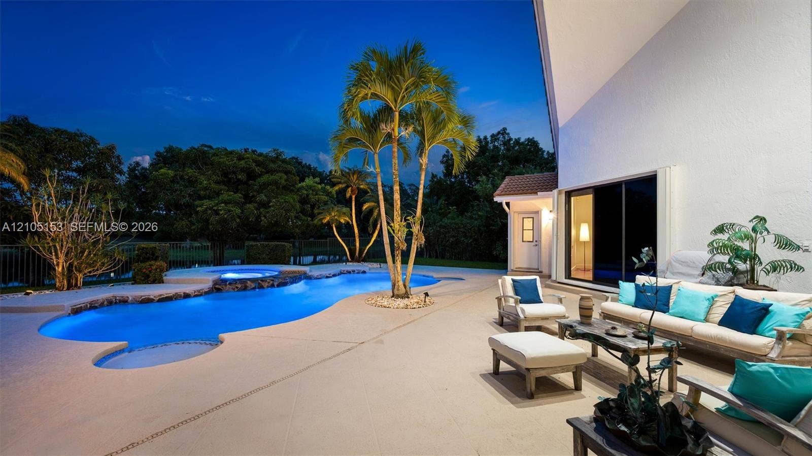 Expansive patio with a resort-style pool, integrated spa, and mature palm trees