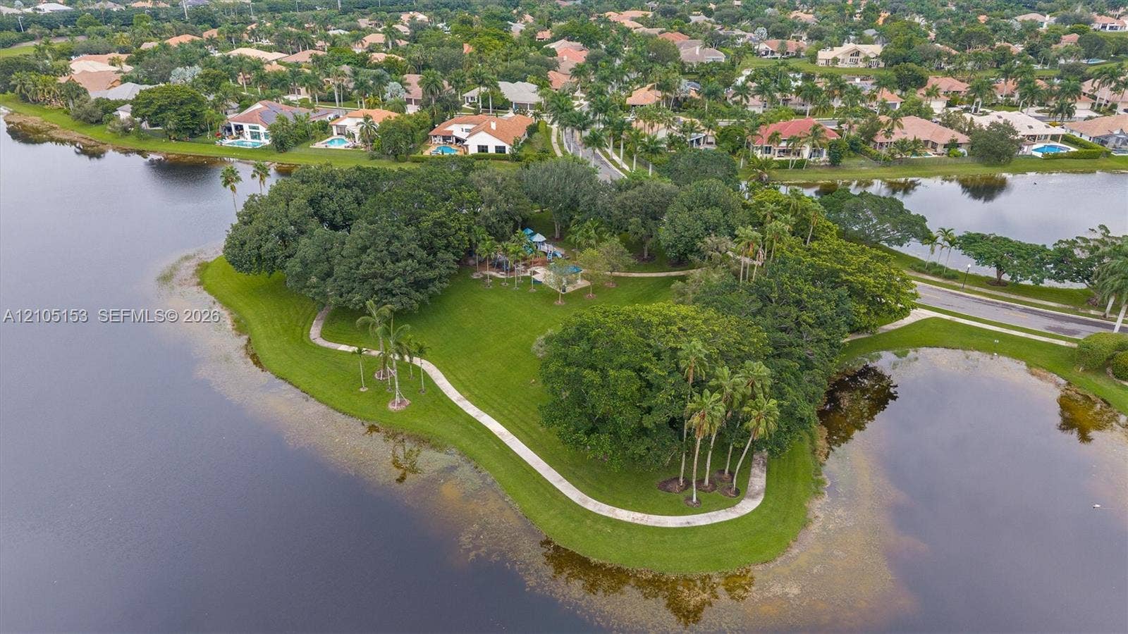 Lakeside property featuring mature trees and a paved path