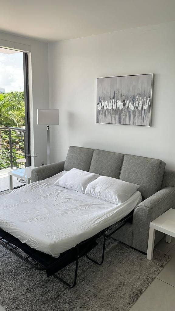 5350 NW 84th Avenue, #303, Doral, FL 33166 Floor-to-ceiling glass door providing outdoor access, neutral-toned tile flooring, and metallic railing on the exterior balcony