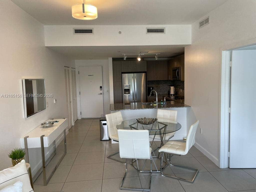 5350 NW 84th Avenue, #303, Doral, FL 33166 Open-concept interior featuring light tile flooring, stainless steel appliances, neutral cabinetry, and a peninsula island with stone surfacing