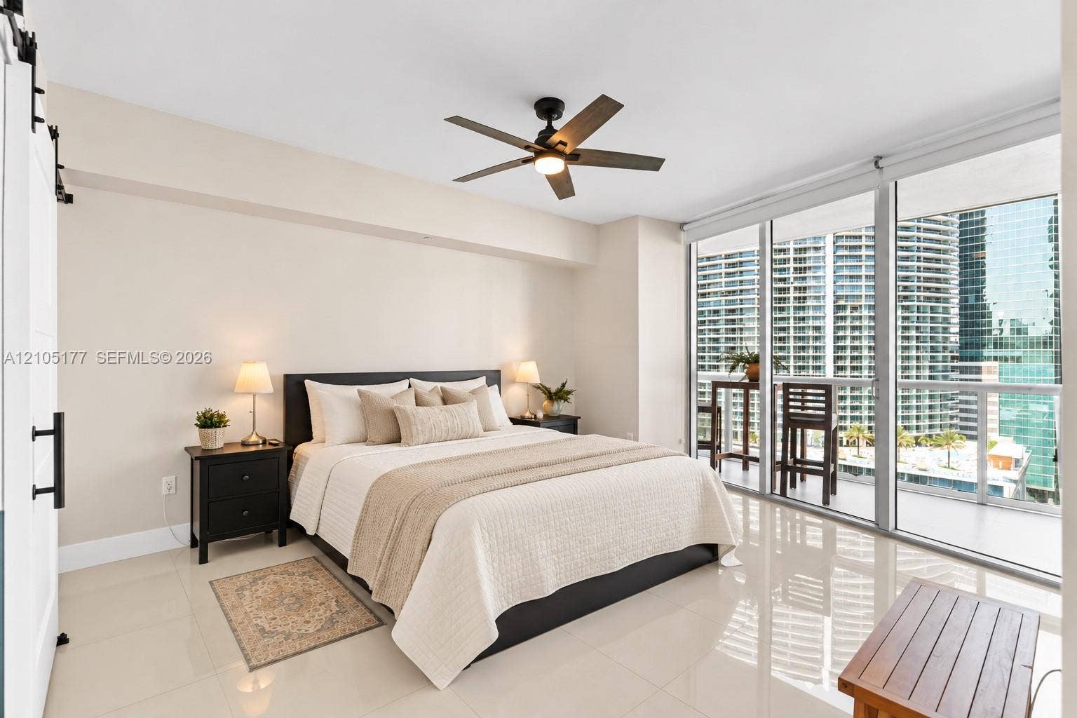 475 Brickell Avenue, #2414, Miami, FL 33131 Floor-to-ceiling glass windows, polished tile flooring, sliding barn door, and a multi-blade ceiling fan with integrated lighting