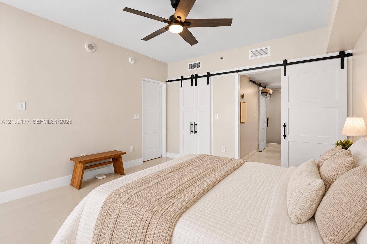 475 Brickell Avenue, #2414, Miami, FL 33131 Neutral wall palette featuring white barn-style sliding doors with matte black hardware, recessed ceiling lighting, and a dark-finish ceiling fan