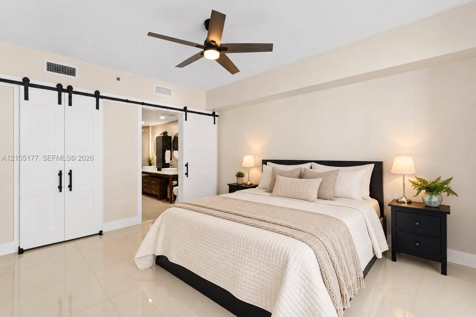 475 Brickell Avenue, #2414, Miami, FL 33131 Neutral-toned room featuring large-format tile flooring, white sliding barn-style doors with matte black hardware, and a modern ceiling fan with integrated lighting