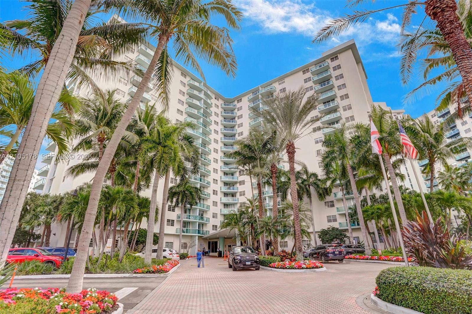 3801 S Ocean Drive, #10G, Hollywood, Hollywood, FL 33019 High-rise building exterior featuring tiered private balconies, paved motor court, and lush tropical landscaping with mature palm trees