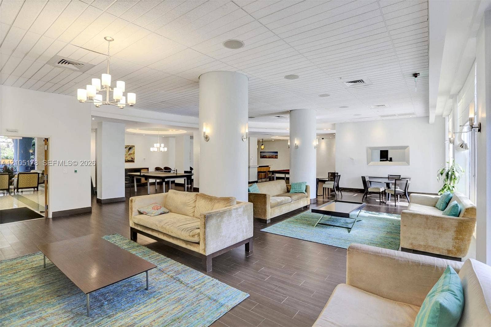 3801 S Ocean Drive, #10G, Hollywood, Hollywood, FL 33019 Open-concept interior featuring structural cylindrical columns, wood-finish plank flooring, recessed ceiling lighting, and multi-arm chandelier fixtures