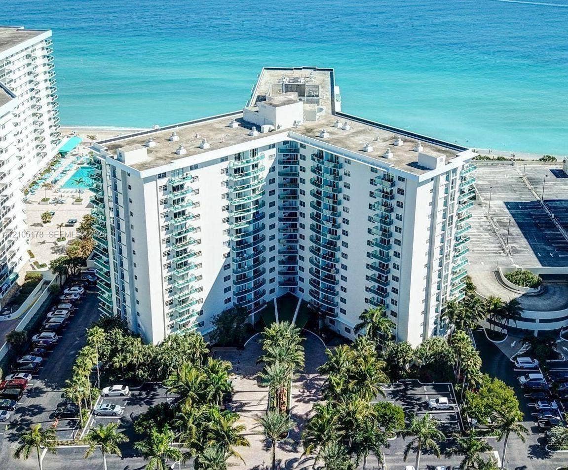 3801 S Ocean Drive, #10G, Hollywood, Hollywood, FL 33019 High-rise residential structure featuring tiered balconies, a paved circular entryway, and extensive tropical landscaping