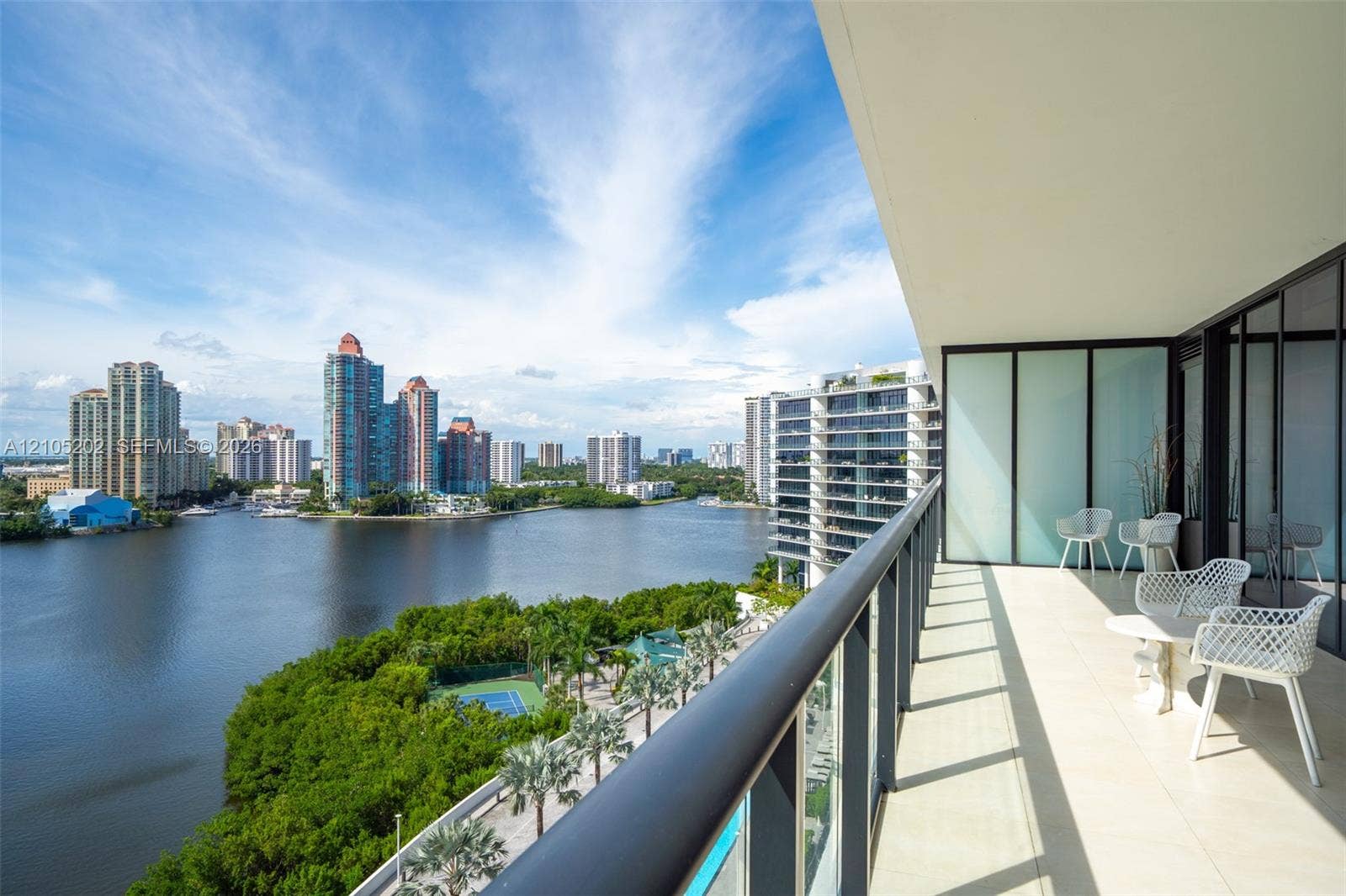 Covered balcony featuring oversized tile flooring, a sleek black metal railing, and expansive floor-to-ceiling glass wall panels