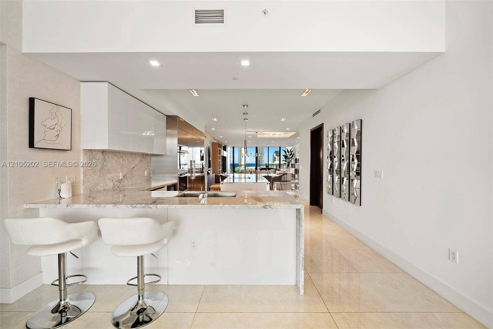 Kitchen featuring a waterfall-edge stone countertop, gloss-finish cabinetry, a stone slab backsplash, recessed ceiling lighting, and tile flooring