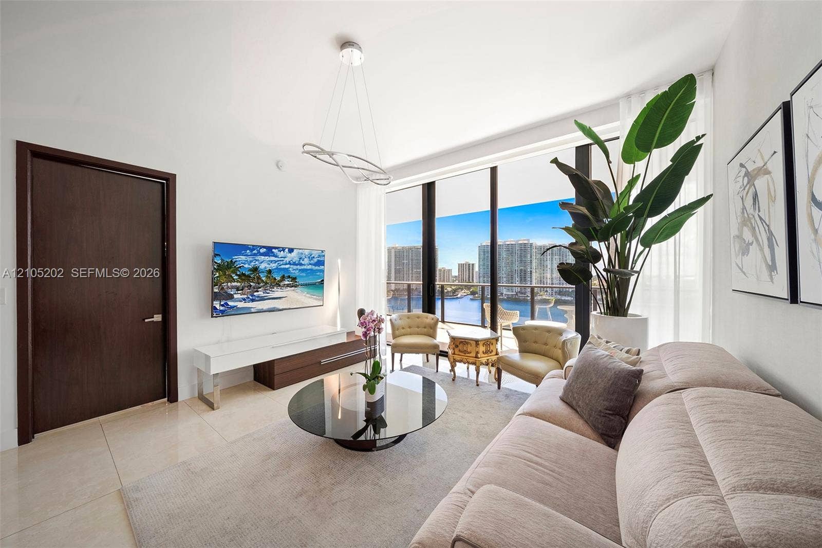 Living area featuring floor-to-ceiling windows, polished tile flooring, a modern sculptural chandelier, and a solid wood entry door