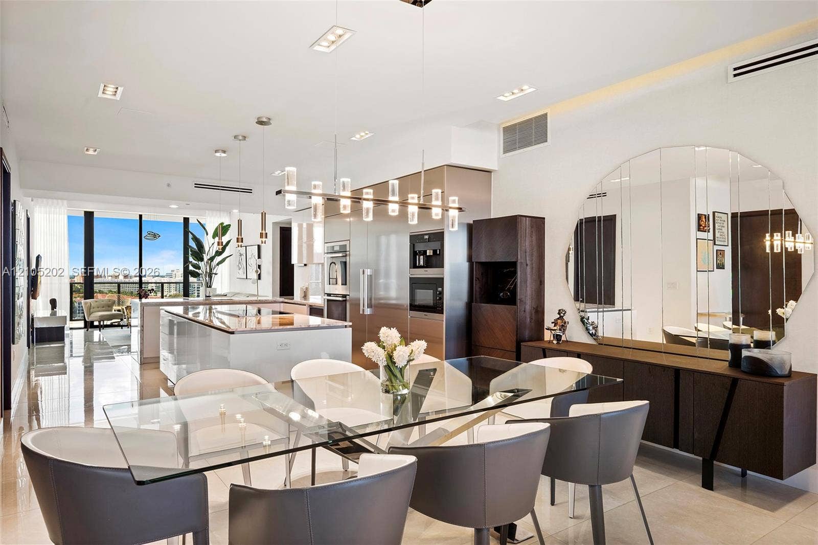 Kitchen featuring a large central island with a stone countertop, built-in stainless steel appliances, multi-light glass pendant fixtures, and polished tile flooring