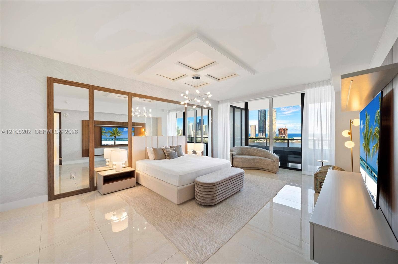 Spacious room featuring polished tile flooring, floor-to-ceiling mirrored panels with wood trim, a recessed tray ceiling, a modern multi-arm chandelier, and a floor-to-ceiling glass wall