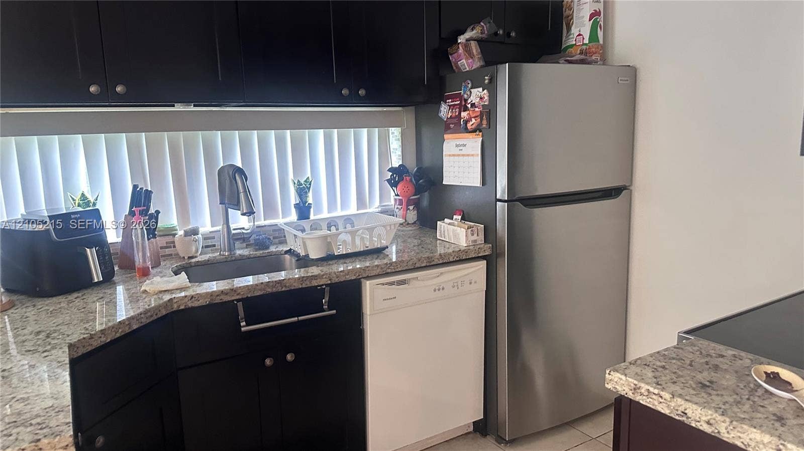17021 N Bay Road, #114, Sunny Isles Beach, Sunny Isles Beach, FL 33160 Kitchen featuring dark cabinetry, stone-finish countertops, stainless steel refrigerator, and undermount sink with a gooseneck faucet