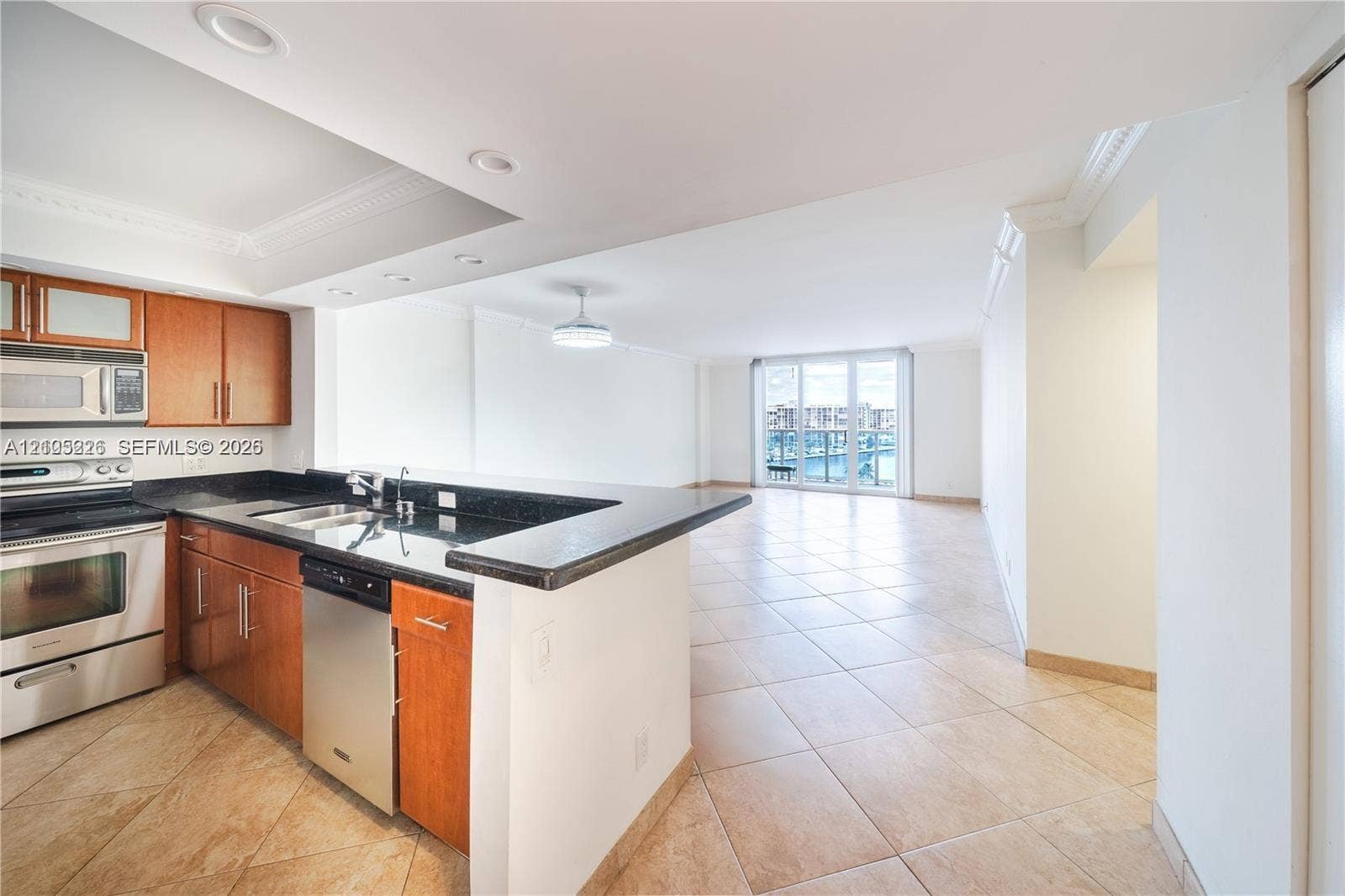 3800 S Ocean Drive, #801, Hollywood, Hollywood, FL 33019 Open floor plan featuring large-format tile flooring, crown molding, and a peninsula-style kitchen counter with built-in cabinetry