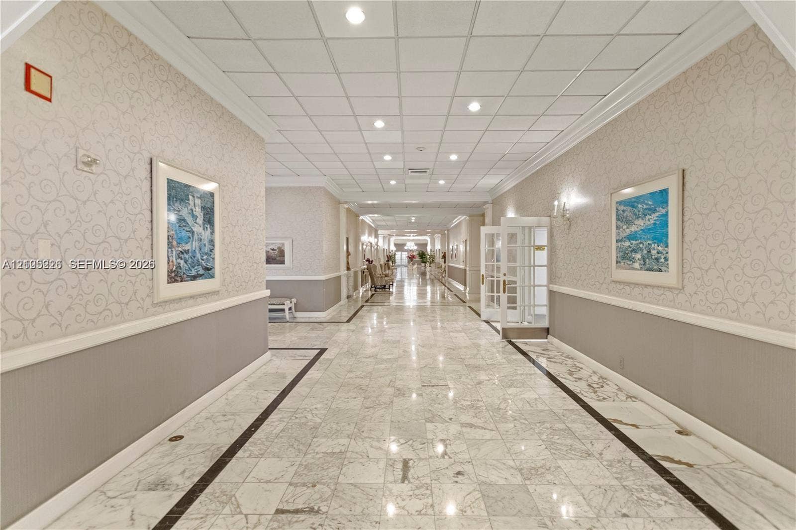 3800 S Ocean Drive, #801, Hollywood, Hollywood, FL 33019 Spacious corridor featuring polished stone flooring with decorative inlay, recessed grid ceiling, custom wall molding, and integrated wall sconces