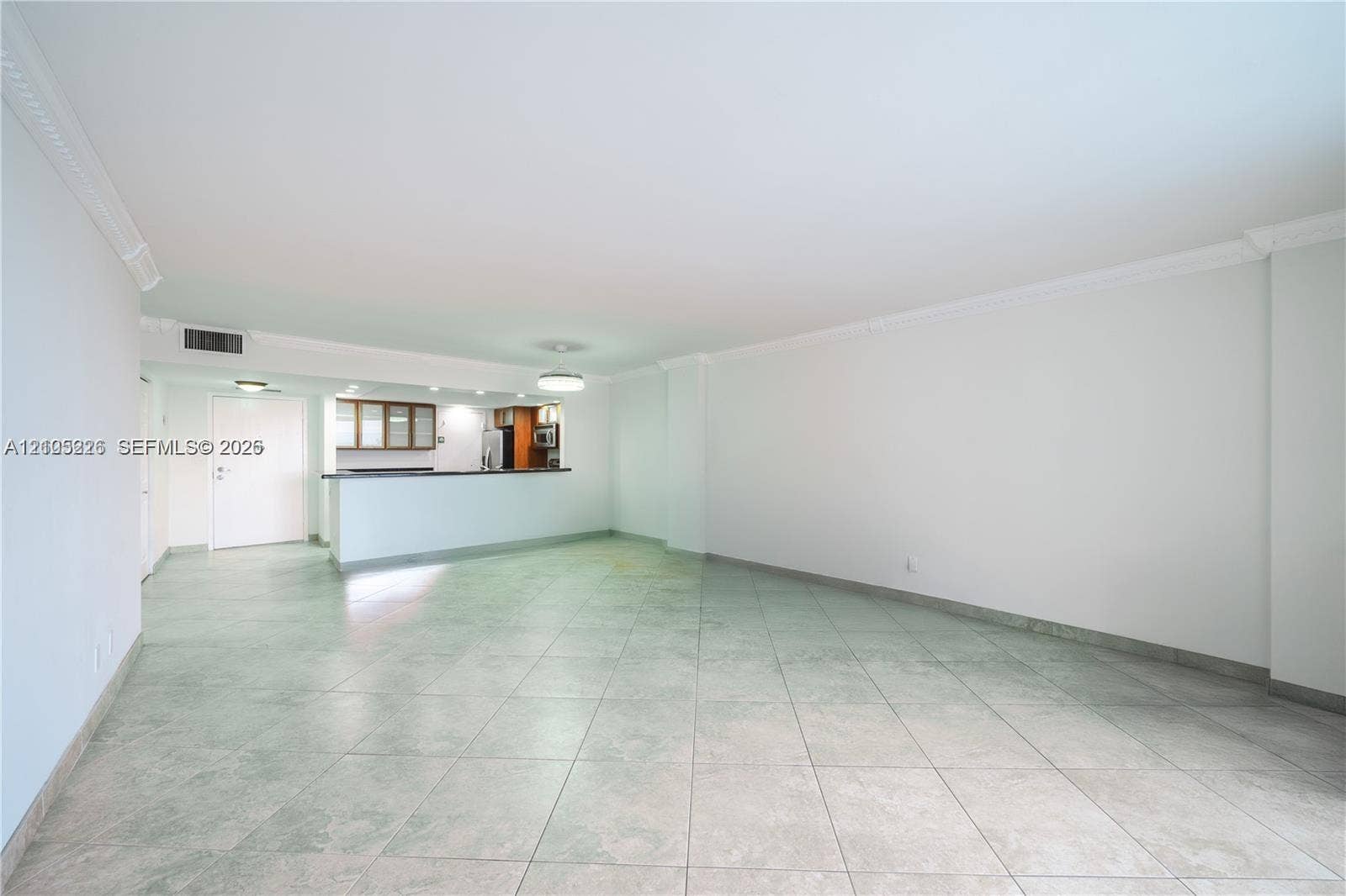 3800 S Ocean Drive, #801, Hollywood, Hollywood, FL 33019 Open-concept living space featuring large-format tile flooring, crown molding, a decorative ceiling fixture, and a sliding glass door providing external access