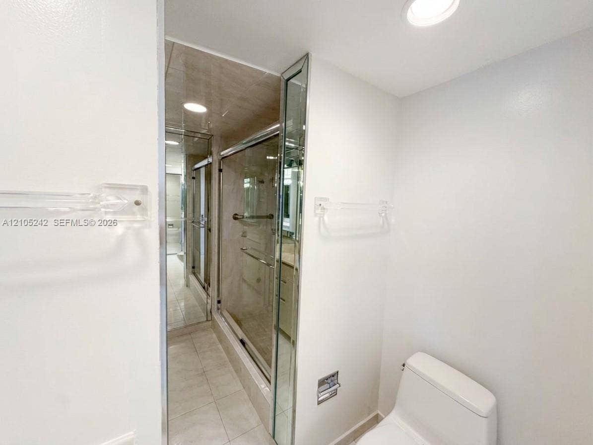 Bathroom featuring a commode, recessed lighting, and a glass-enclosed shower