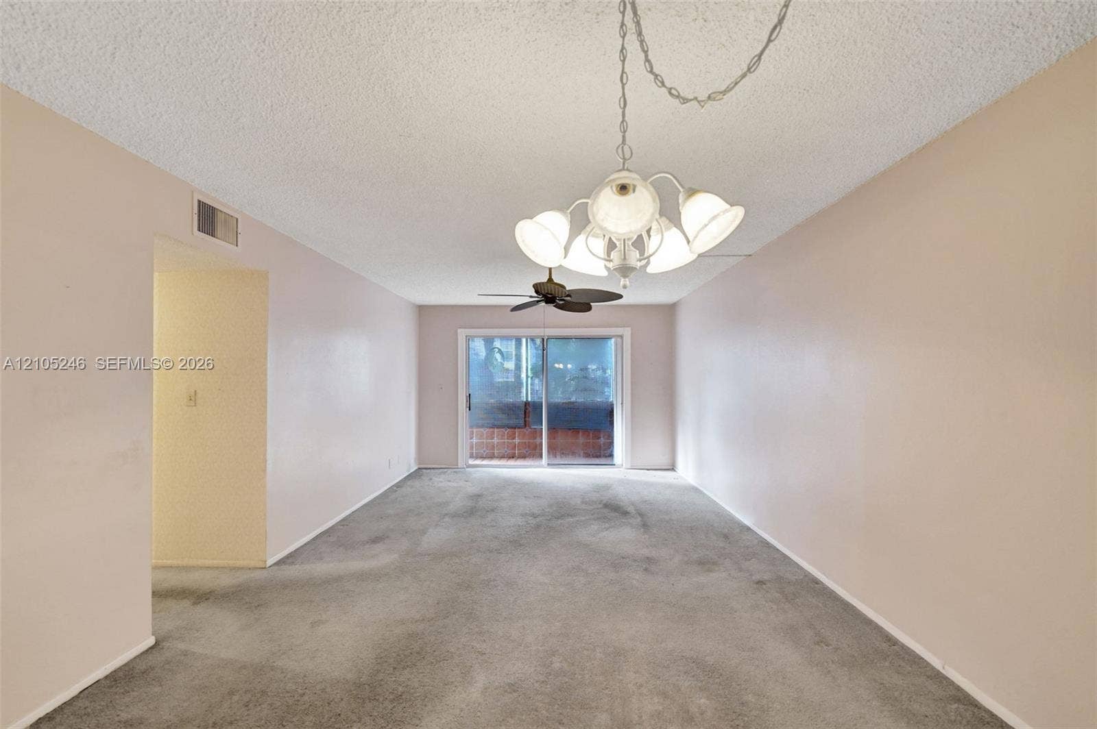 1400 Tallwood Avenue, #207, Hollywood, FL 33021 Interior space featuring a multi-arm chandelier with frosted glass shades, a ceiling fan, carpeted flooring, and a sliding glass door
