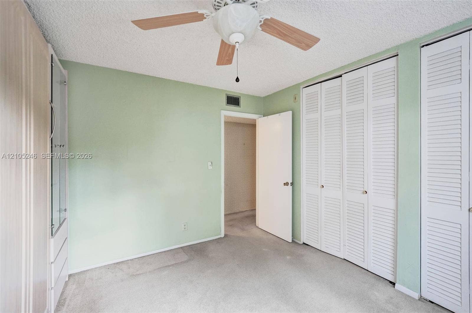 1400 Tallwood Avenue, #207, Hollywood, FL 33021 Room featuring dual sets of floor-to-ceiling louvered-door closets, built-in cabinetry with glass-front shelving, and a ceiling fan with integrated lighting