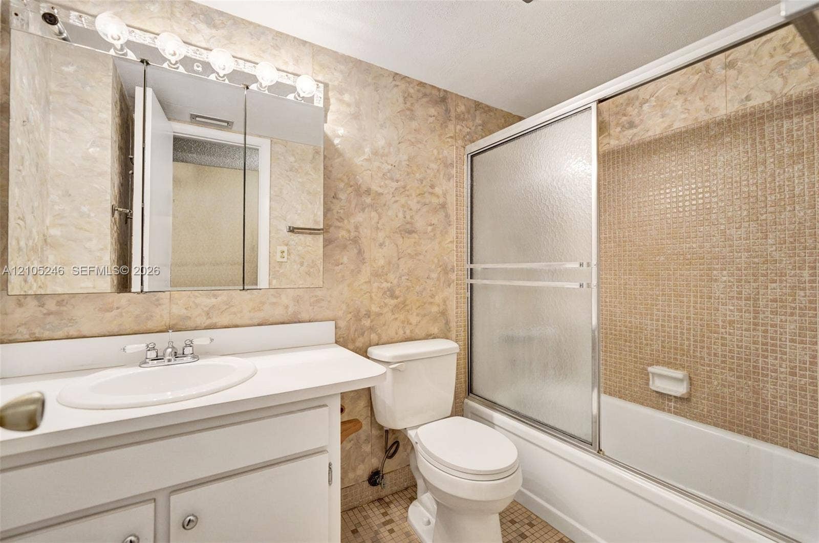 1400 Tallwood Avenue, #207, Hollywood, FL 33021 Bathroom featuring a white vanity with an integrated sink, tri-fold medicine cabinet, five-light fixture, and a bathtub with sliding glass doors and tiled surround