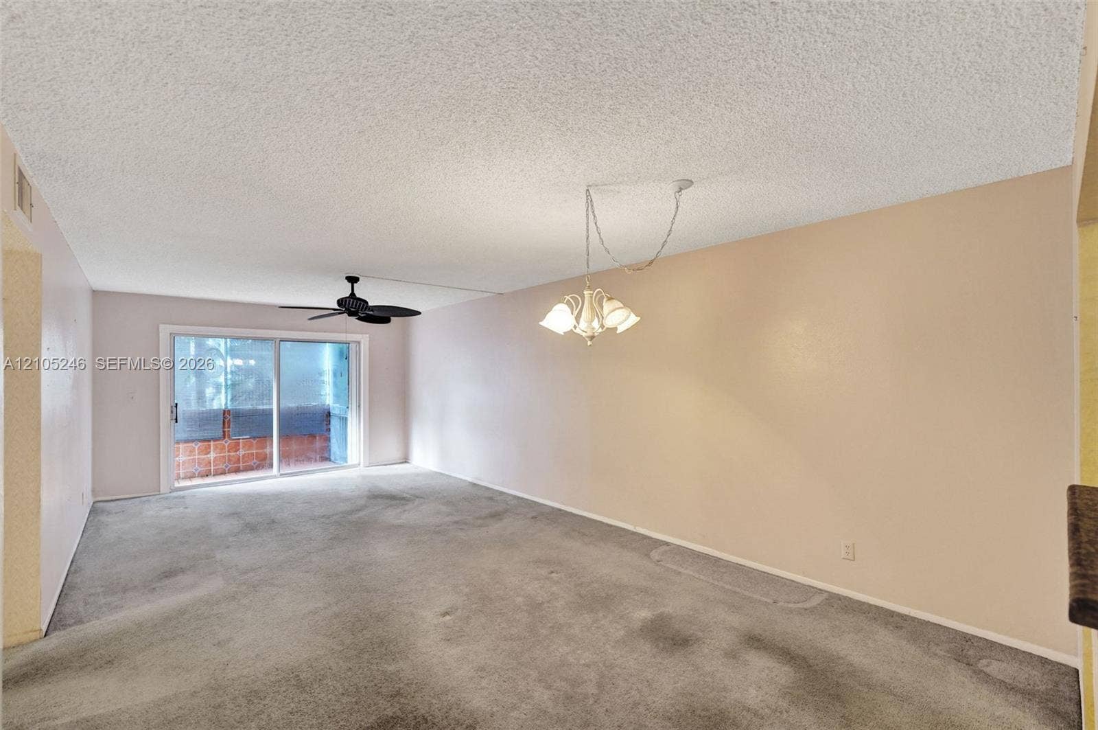 1400 Tallwood Avenue, #207, Hollywood, FL 33021 Interior space featuring sliding glass doors, a central ceiling fan with integrated lighting, and a multi-arm chandelier