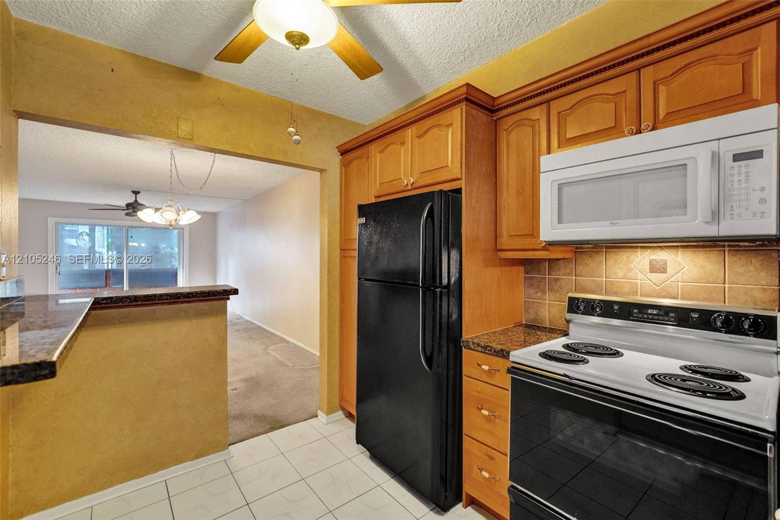 1400 Tallwood Avenue, #207, Hollywood, FL 33021 Kitchen featuring raised-panel wood cabinetry, stone-surface countertops, tile backsplash, built-in microwave, and ceiling fan