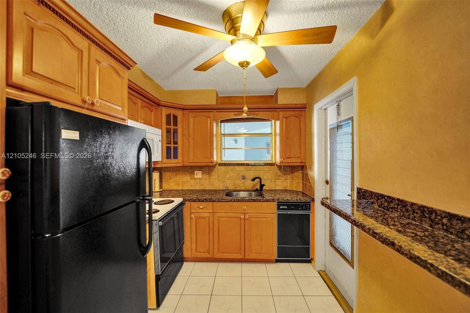 1400 Tallwood Avenue, #207, Hollywood, FL 33021 Kitchen featuring wood cabinetry, stone-finish countertops, tile backsplash, tile flooring, and ceiling fan with integrated light fixture