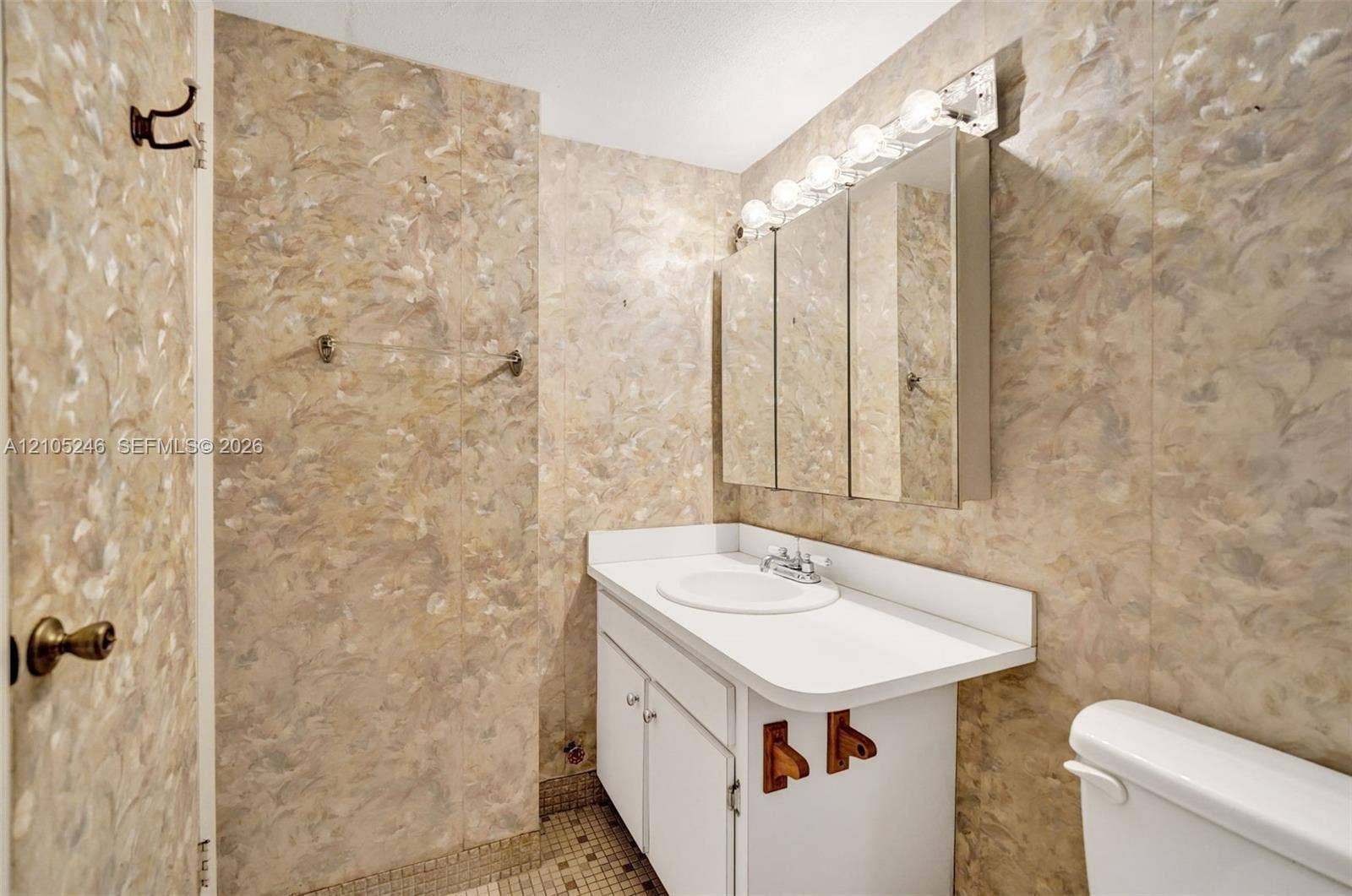 1400 Tallwood Avenue, #207, Hollywood, FL 33021 Bathroom featuring a vanity with an integrated basin, a tri-fold mirrored medicine cabinet, a multi-bulb light fixture, and textured wall coverings