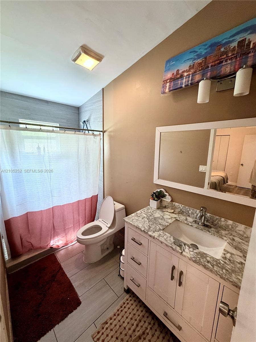 700 NW 17th Terrace, Pompano Beach, FL 33069 Vanity with integrated sink and marble-look countertop, white framed mirror, and rectangular floor tiles