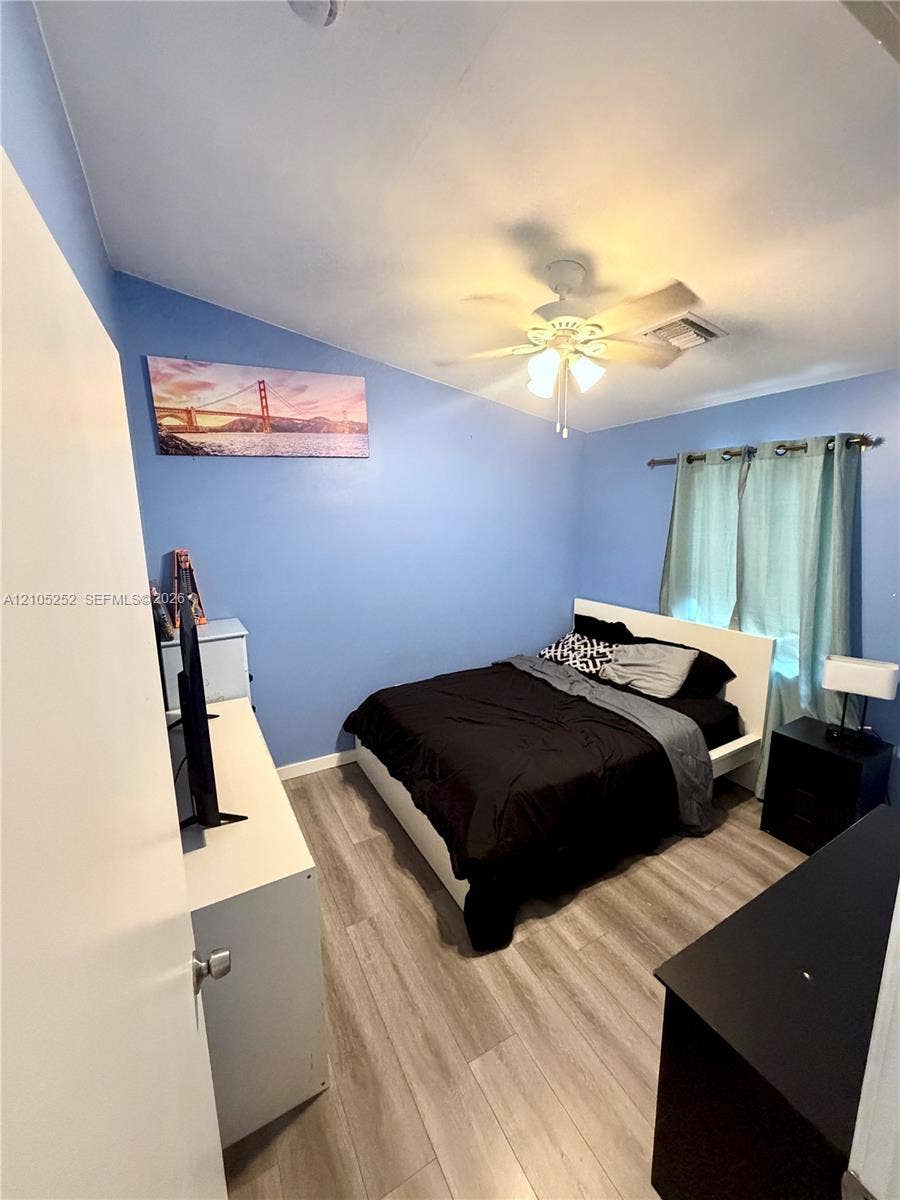 700 NW 17th Terrace, Pompano Beach, FL 33069 Wood-finish flooring, ceiling fan, and window with curtains