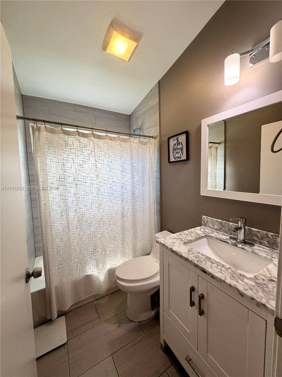 700 NW 17th Terrace, Pompano Beach, FL 33069 White vanity with double-door cabinetry, integrated sink, and stone-finish countertop