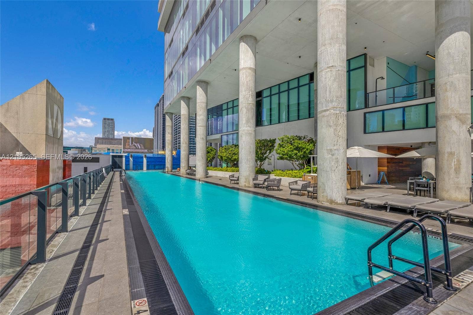 398 NE 5th Street, #2219, Miami, FL 33132 Elevated lap pool featuring glass perimeter railings, concrete structural pillars, and concrete terrace decking