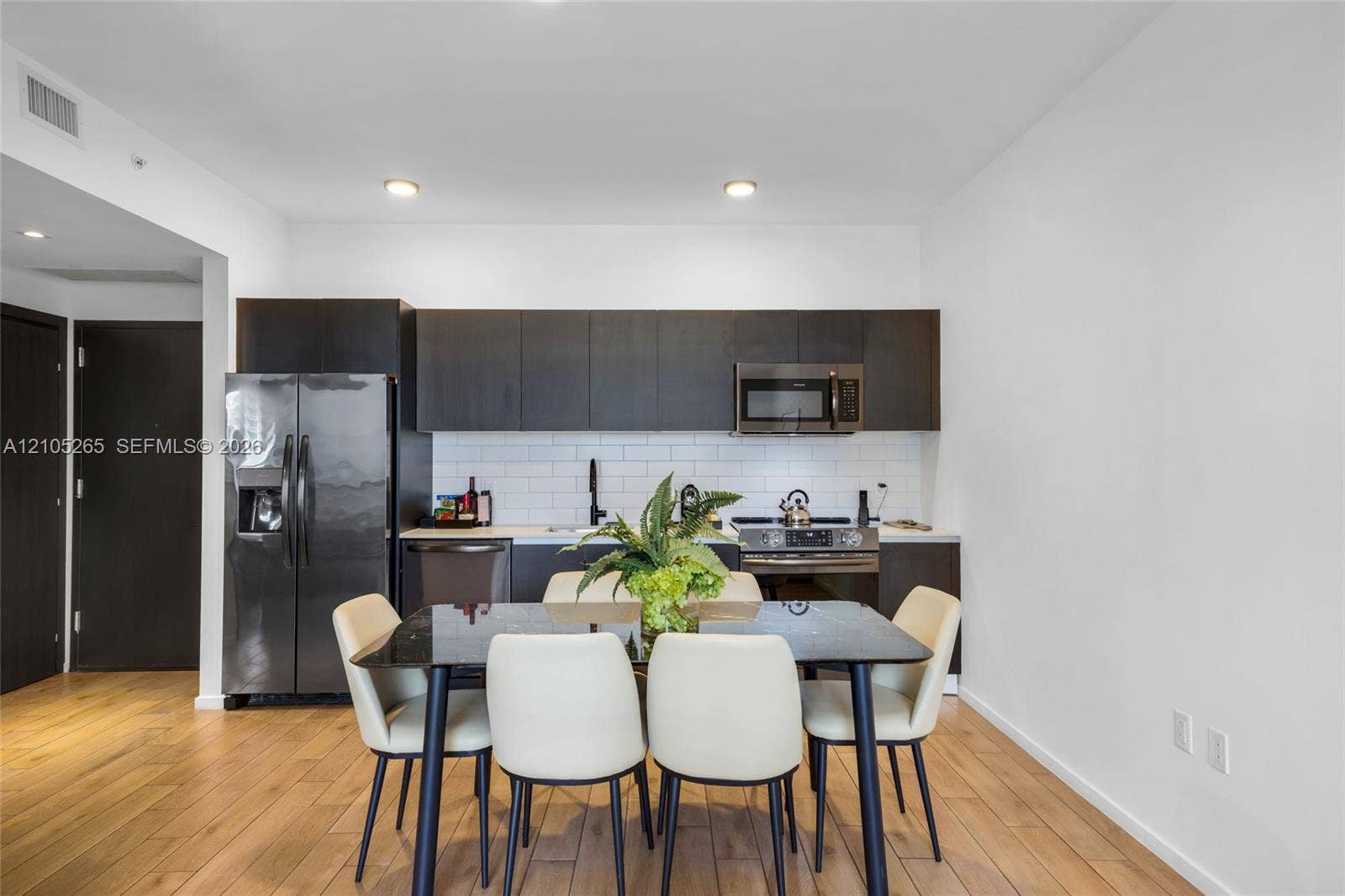398 NE 5th Street, #2219, Miami, FL 33132 Kitchen featuring flat-panel cabinetry, a white subway tile backsplash, stainless steel appliances, and wood-finish flooring