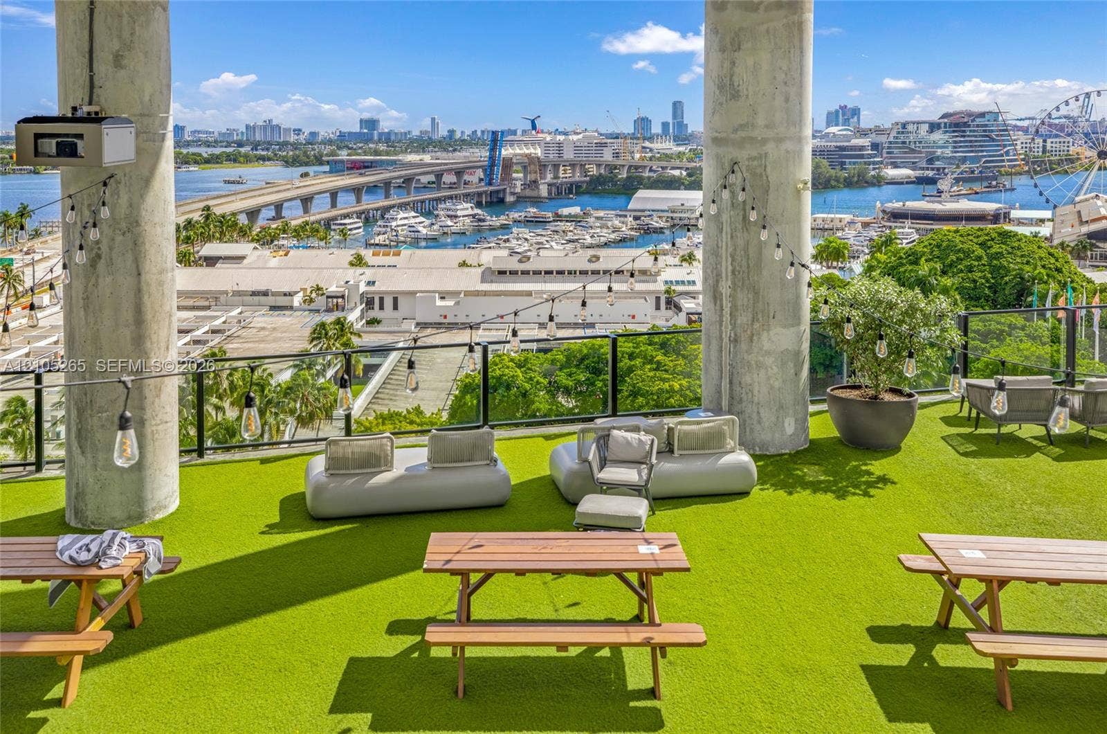 398 NE 5th Street, #2219, Miami, FL 33132 Rooftop terrace featuring synthetic turf flooring, exposed structural concrete pillars, and a glass panel railing