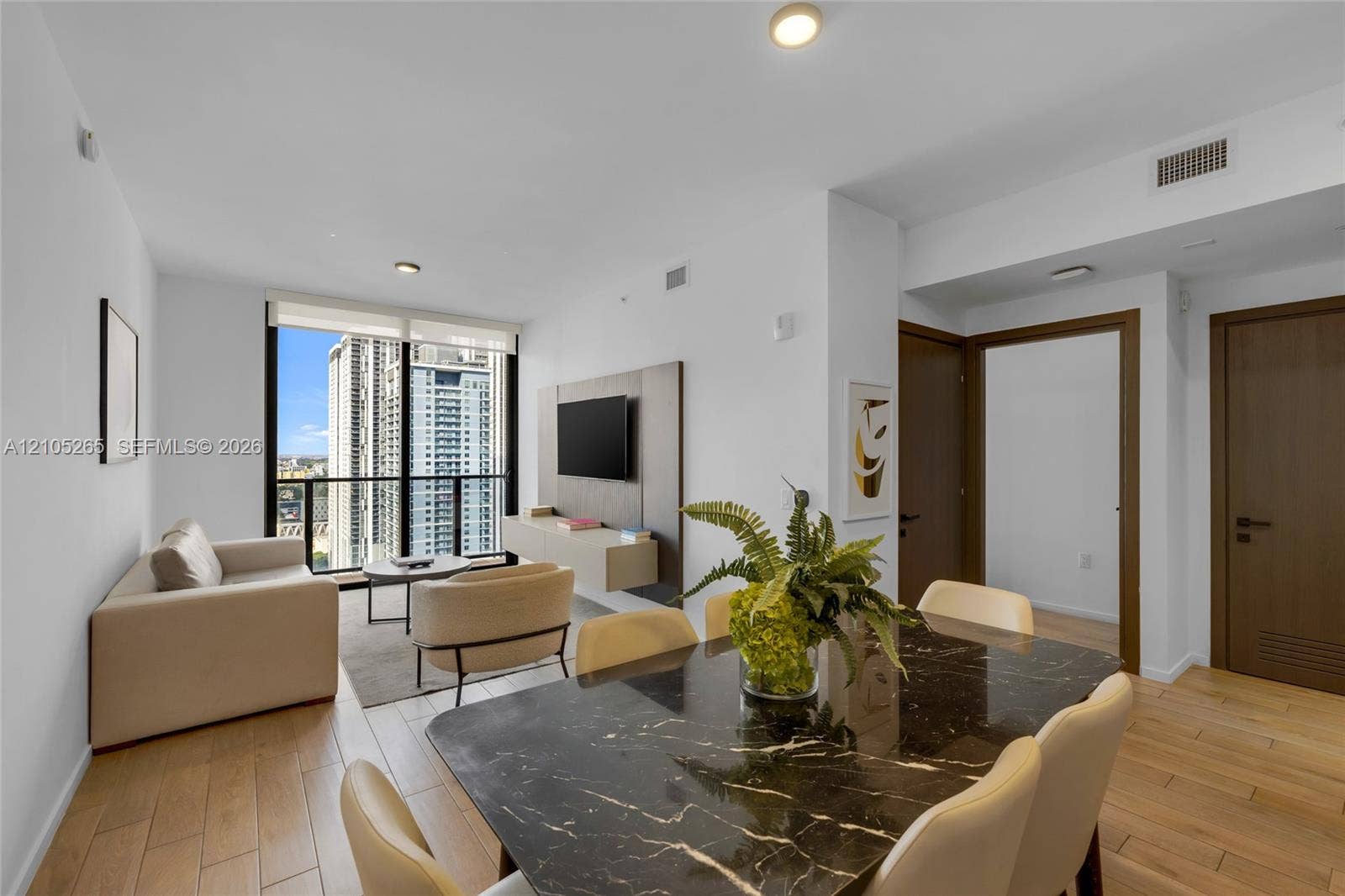 398 NE 5th Street, #2219, Miami, FL 33132 Open-concept living space featuring wood-finish flooring, floor-to-ceiling windows, and a built-in wall-mounted media console