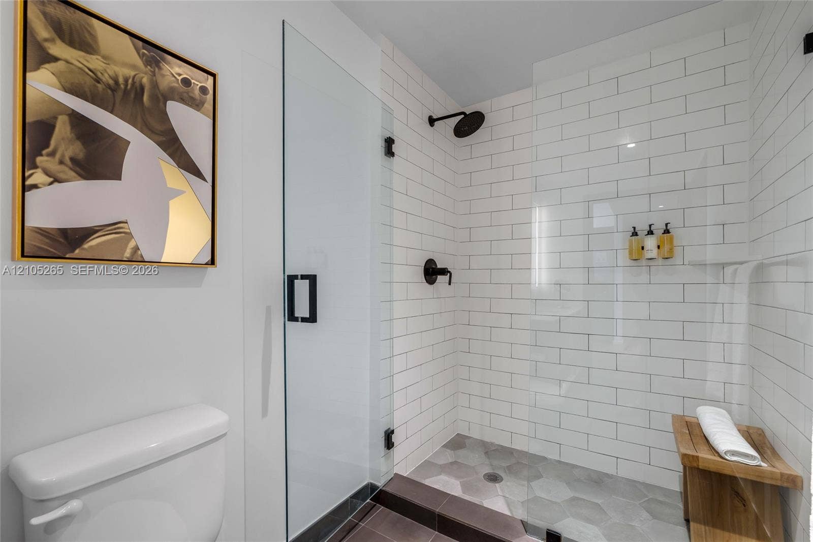 398 NE 5th Street, #2219, Miami, FL 33132 Walk-in shower with white subway tile surround, matte black rainfall shower head, hexagon floor tile, glass door, and built-in stone corner shelf