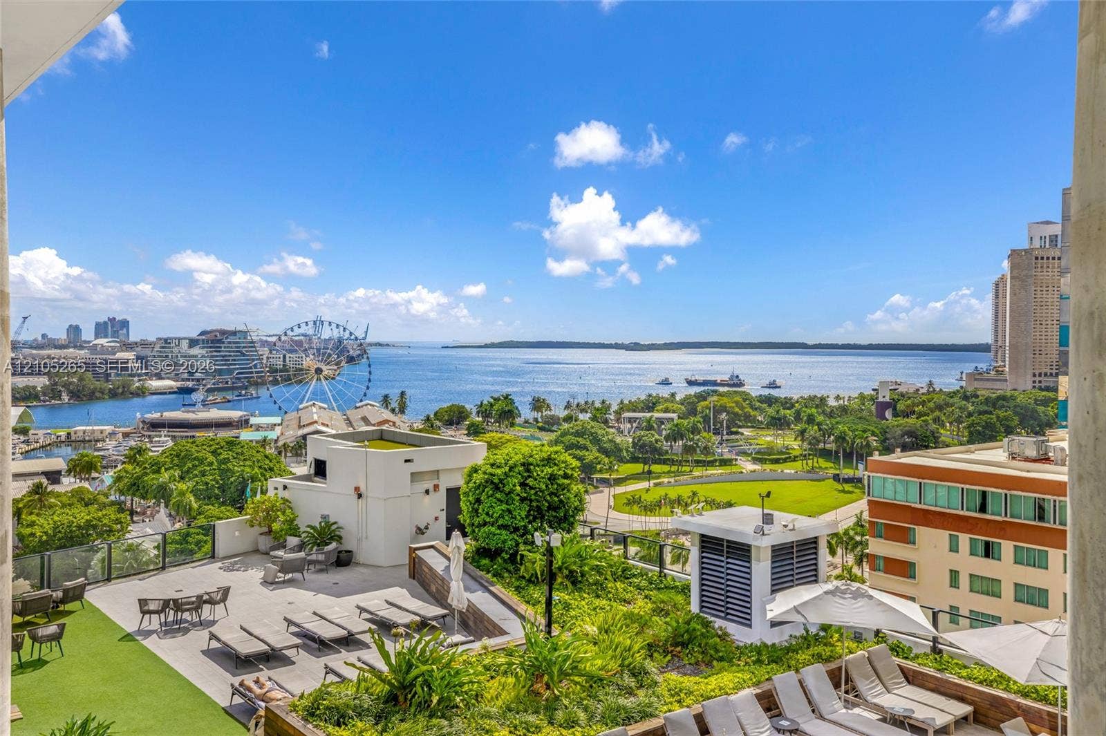 398 NE 5th Street, #2219, Miami, FL 33132 Elevated rooftop terrace featuring synthetic turf, stone-paver flooring, built-in planters, and panoramic water and urban harbor scenery