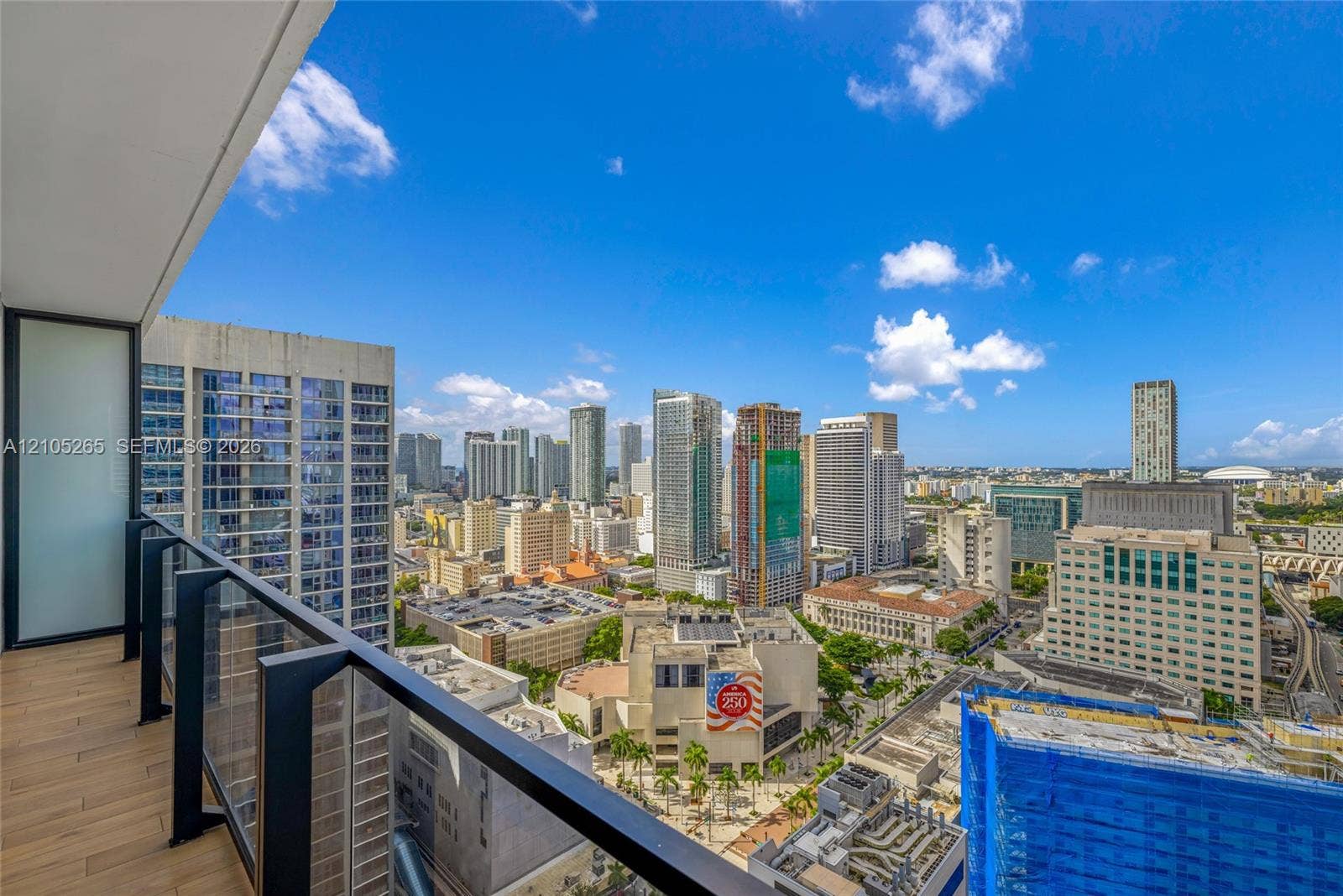 398 NE 5th Street, #2219, Miami, FL 33132 Private balcony featuring wood-finish flooring and a tempered glass railing, showcasing an expansive urban skyline