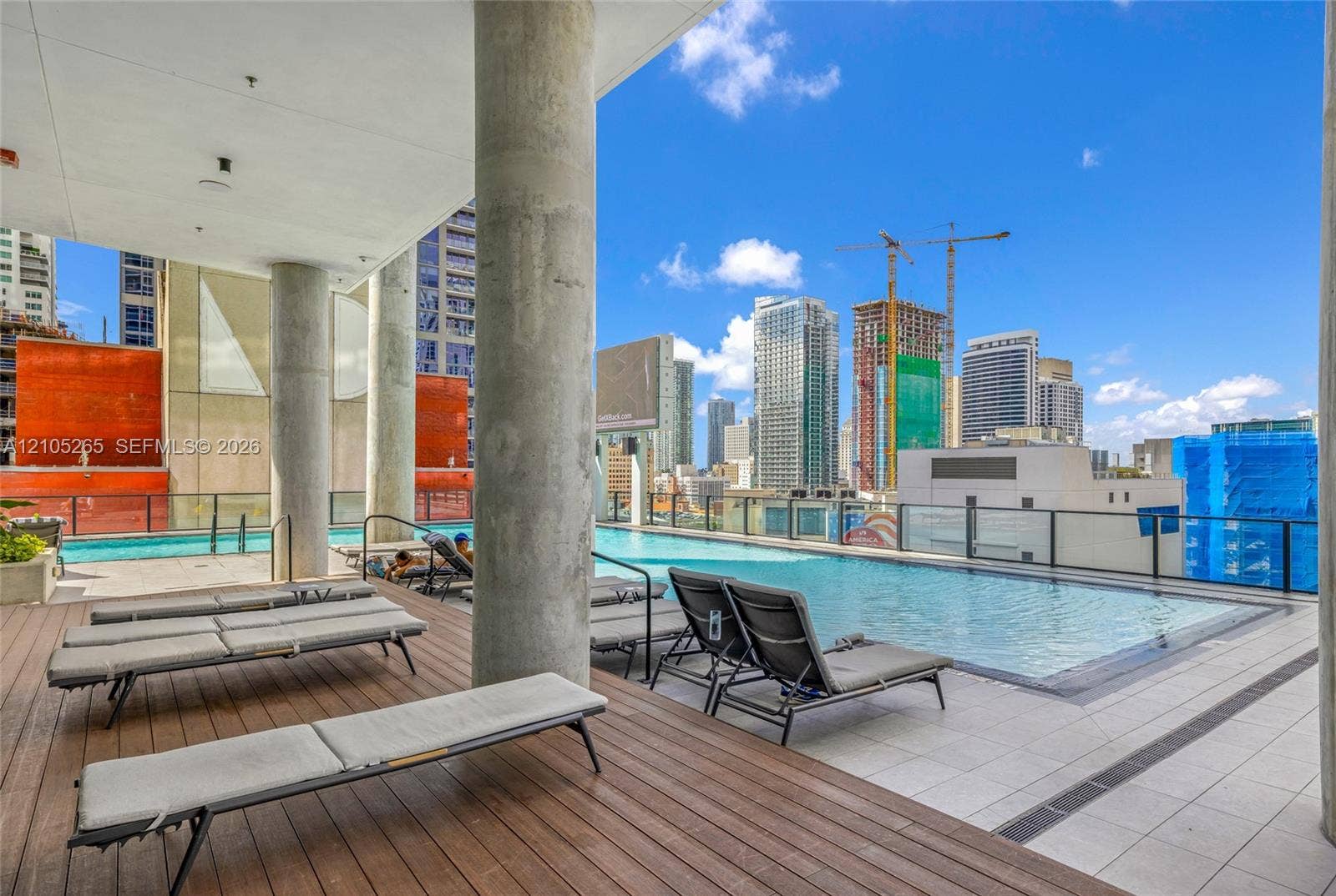 398 NE 5th Street, #2219, Miami, FL 33132 Rooftop swimming pool with tile surround, wood-finish deck, concrete structural columns, and glass panel railing