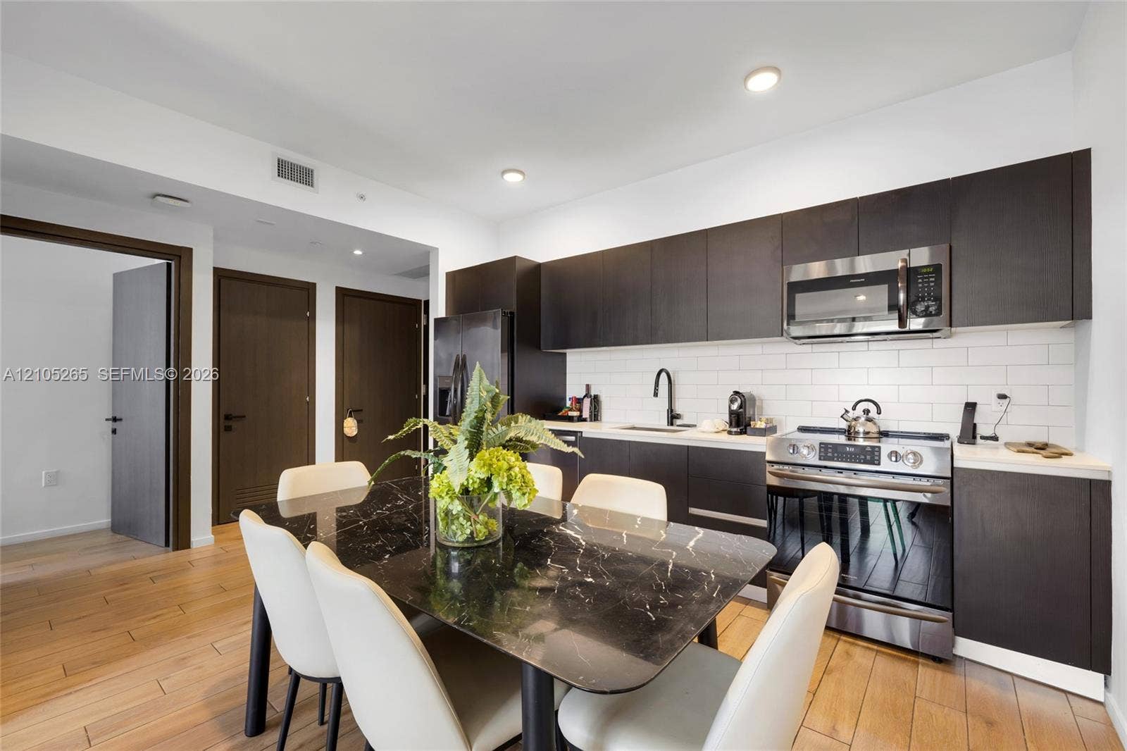 398 NE 5th Street, #2219, Miami, FL 33132 Kitchen featuring dark cabinetry, white subway tile backsplash, stainless steel appliances, and wood-finish flooring
