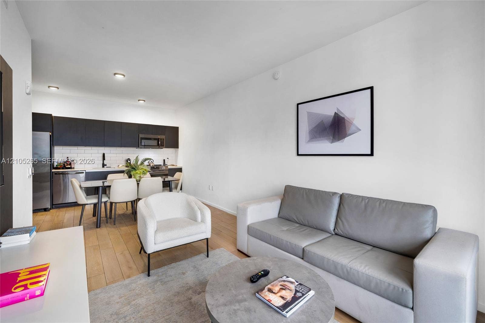 398 NE 5th Street, #2219, Miami, FL 33132 Modern kitchen featuring matte black flat-panel cabinetry, white subway tile backsplash, stainless steel appliances, and wood-finish flooring