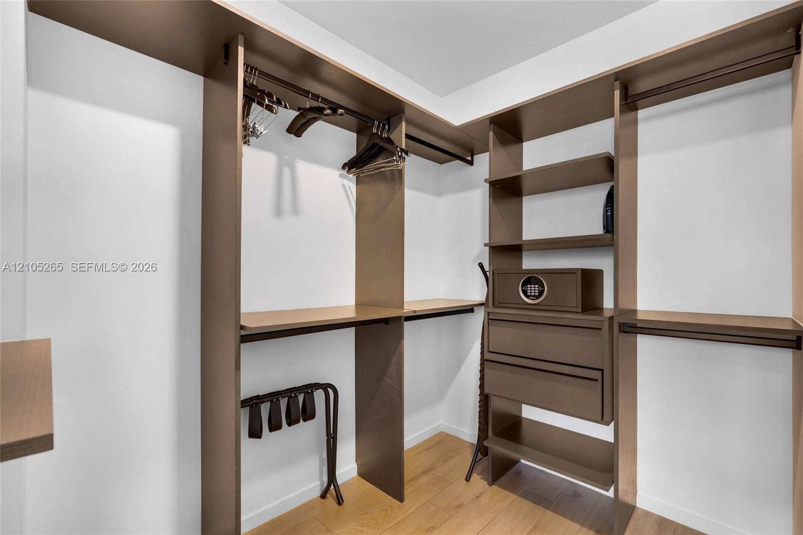 398 NE 5th Street, #2219, Miami, FL 33132 Walk-in closet featuring custom laminate shelving, integrated hanging rods, built-in drawer storage, and wood-finish flooring
