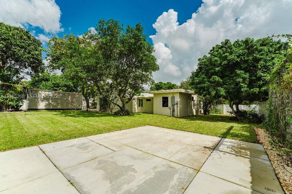 230 Miami Springs Avenue, Miami Springs, FL 33166 Expansive concrete patio with a lush green lawn and mature trees