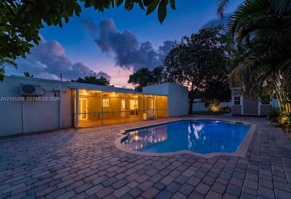 230 Miami Springs Avenue, Miami Springs, FL 33166 Paved patio surrounding a freeform pool, screened patio with overhead lighting, and a detached structure